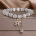 Women's white cat's eye bracelet with flower tassel and safety buckle pendant on wrist