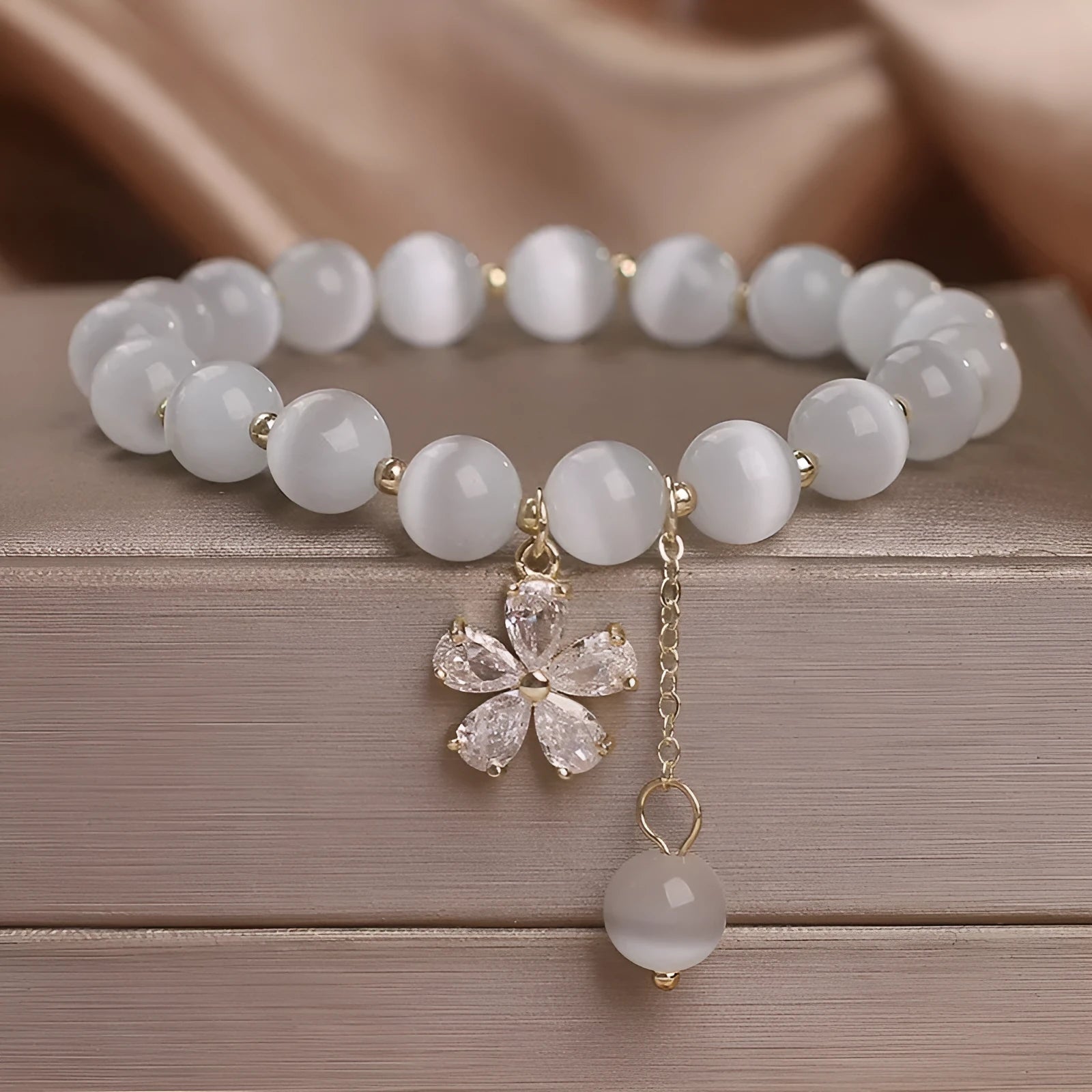 Women's white cat's eye bracelet with flower tassel and safety buckle pendant on wrist