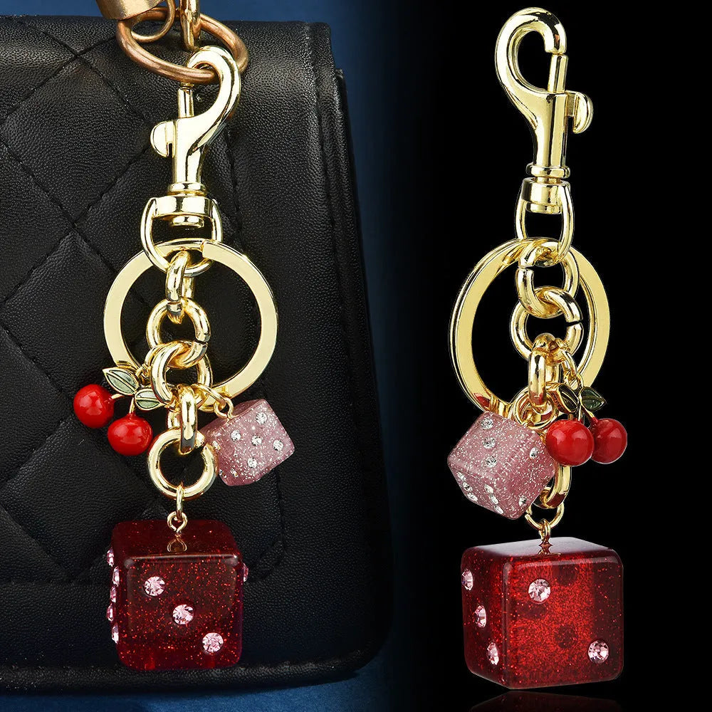 Square metal keychain pendant with a cerise two-tone dice pattern.