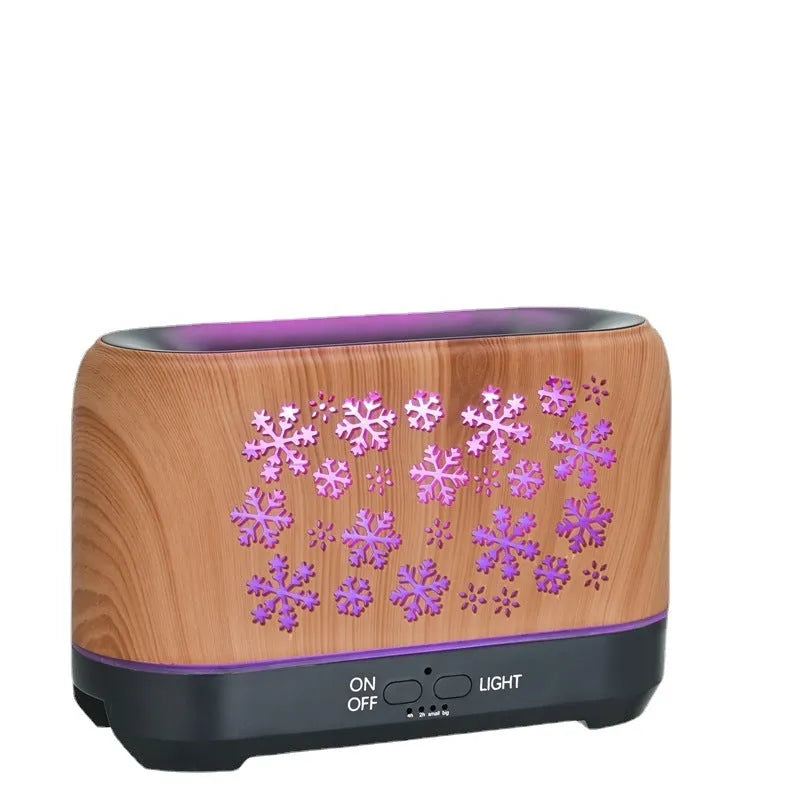 Colourful snowflake pattern aromatherapy humidifier with glowing flame effect and remote control on a desktop.