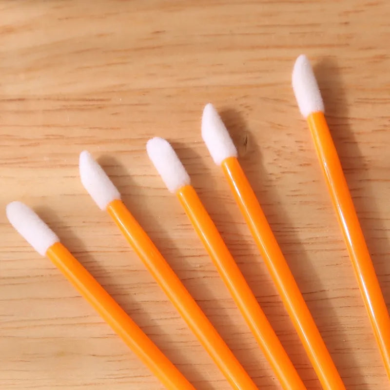 Pack of disposable lip brush applicators with flocked heads and black handles on a white background.
