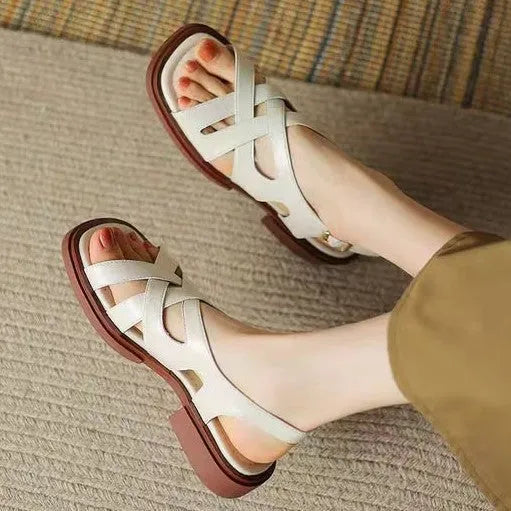 Women's glossy patent leather square toe sandals with cross strap on a brown background