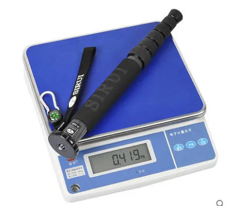 Black carbon fibre telescopic camera monopod extended to full height on a grey background.