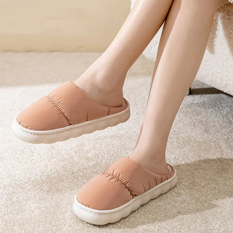 Pair of down cotton indoor slippers with artificial leather upper and thick rubber sole.
