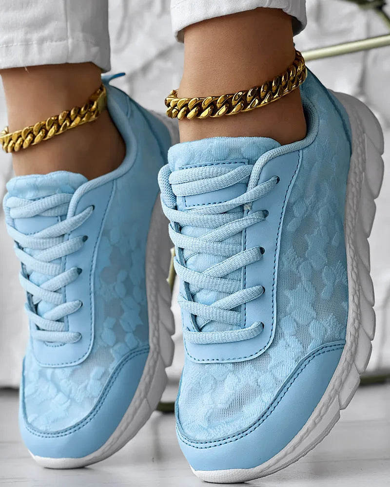 Women's white canvas running shoe with flat heel and round toe on a neutral background.
