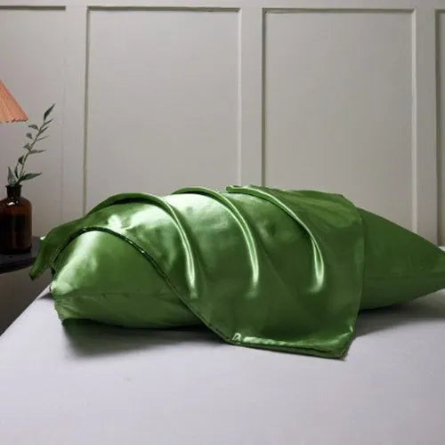 Dark blue polyester satin pillowcase with envelope closure on a bed with white sheets
