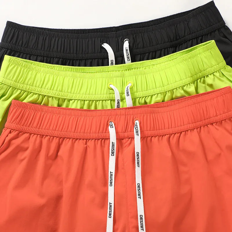Men's loose beach shorts in orange, fluorescent green, and black colours with elastic waist