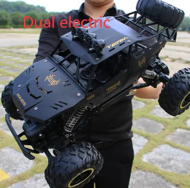 Large black or silver 4WD remote control climbing car on off-road terrain with wireless remote.