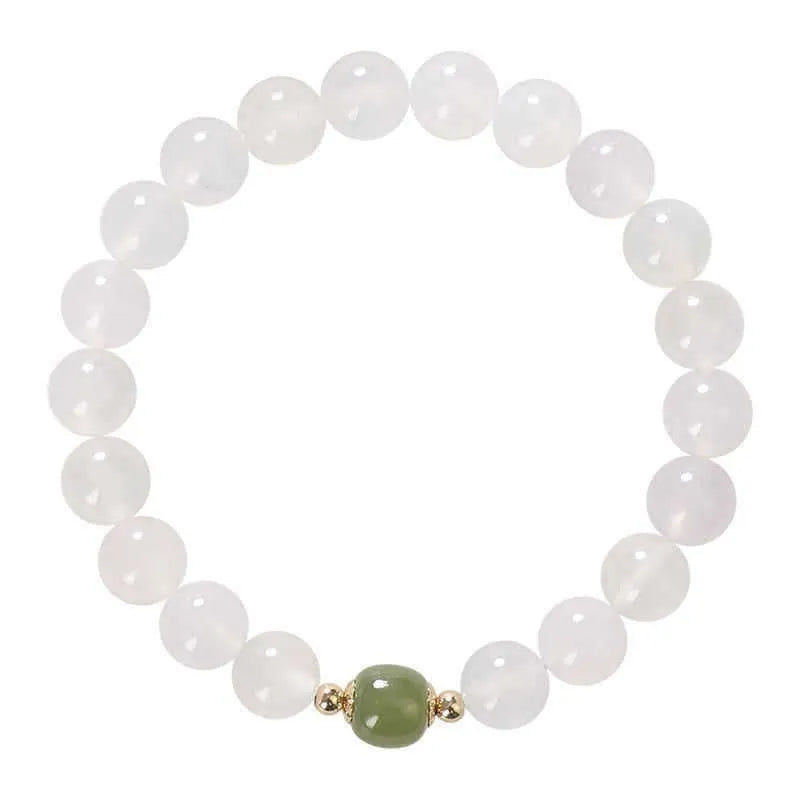 Handmade white agate and crystal bracelet with red cinnabar inlay on a wrist.