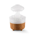 Wood grain white rain cloud shaped humidifier and essential oil diffuser with LED lights on a table.