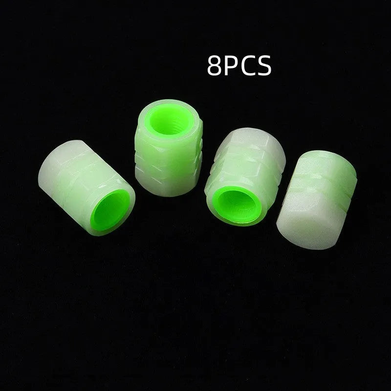 Set of four luminous rubber car valve caps glowing on a dark background.