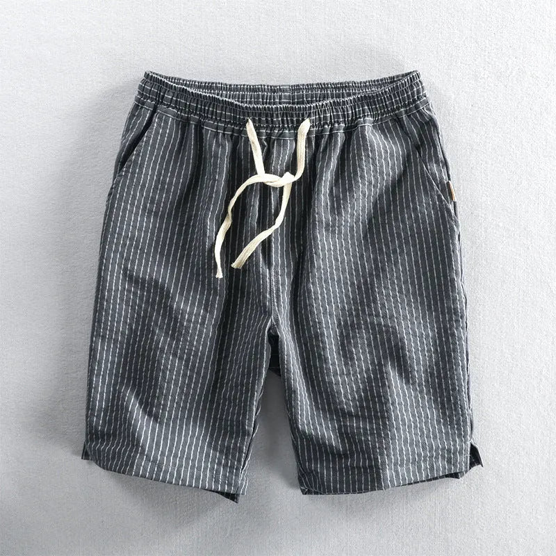 Man wearing striped light blue cotton casual shorts with a mid waist and loose straight fit.