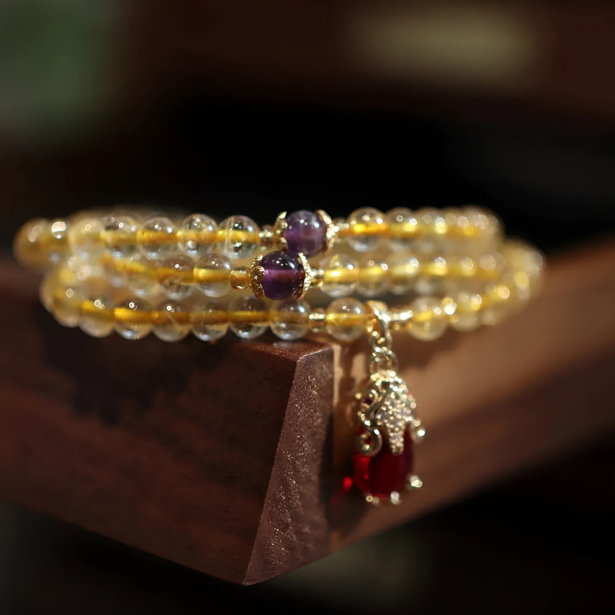 Natural quartz bracelet with three gold-coloured rings and hanging chopstick charms in a Chinese style.
