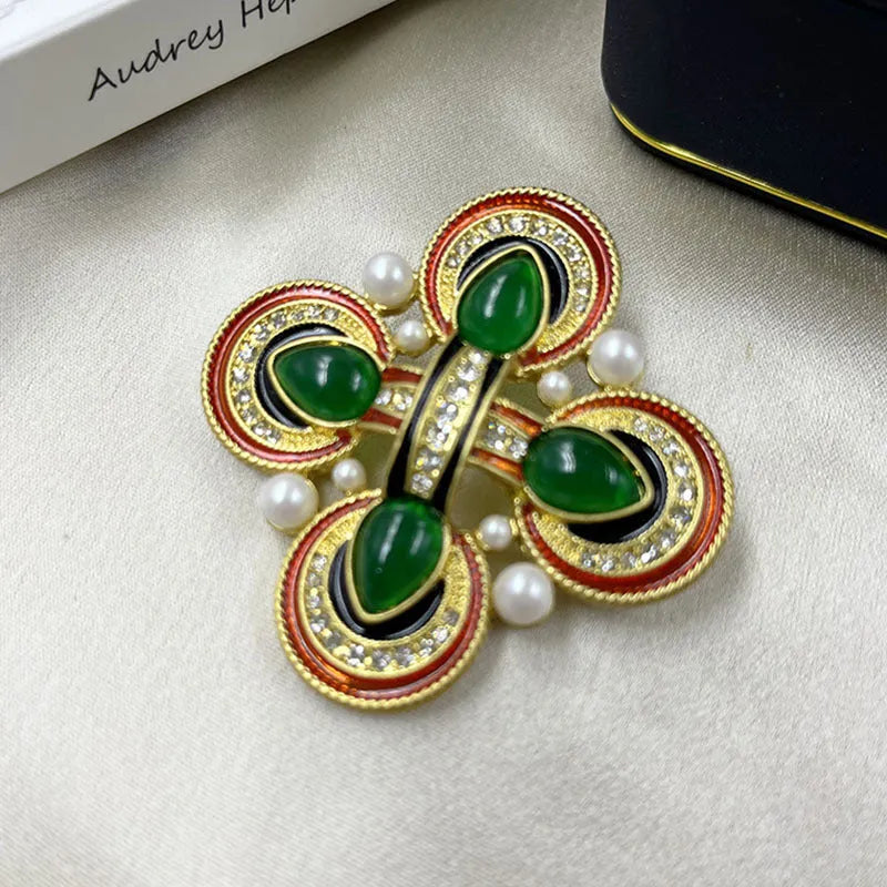 Close-up of a detailed baroque cross brooch with crystal accents on a zinc alloy base.