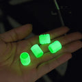 Set of four luminous rubber car valve caps glowing on a dark background.