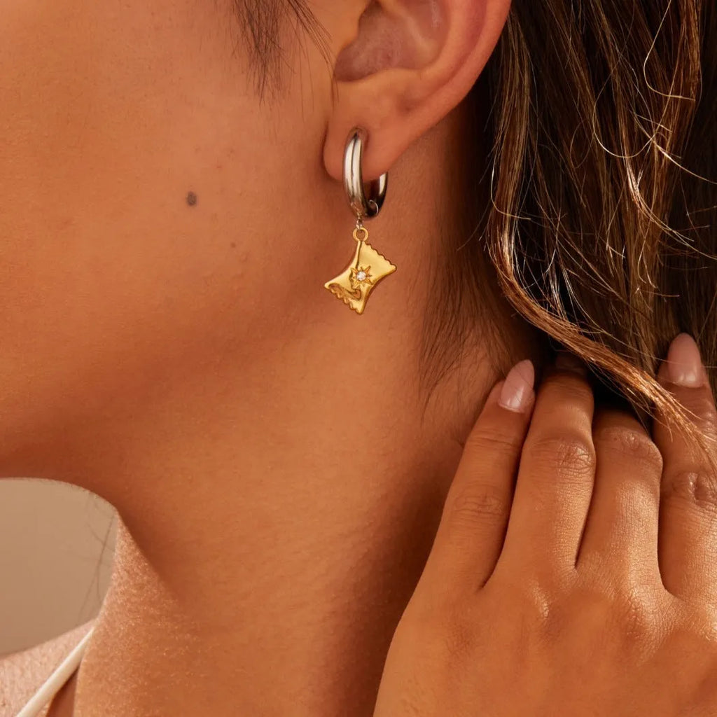 A pair of stainless steel earrings with an 18K gold colour finish, shown in a Christmas tree shape and a heart shape.
