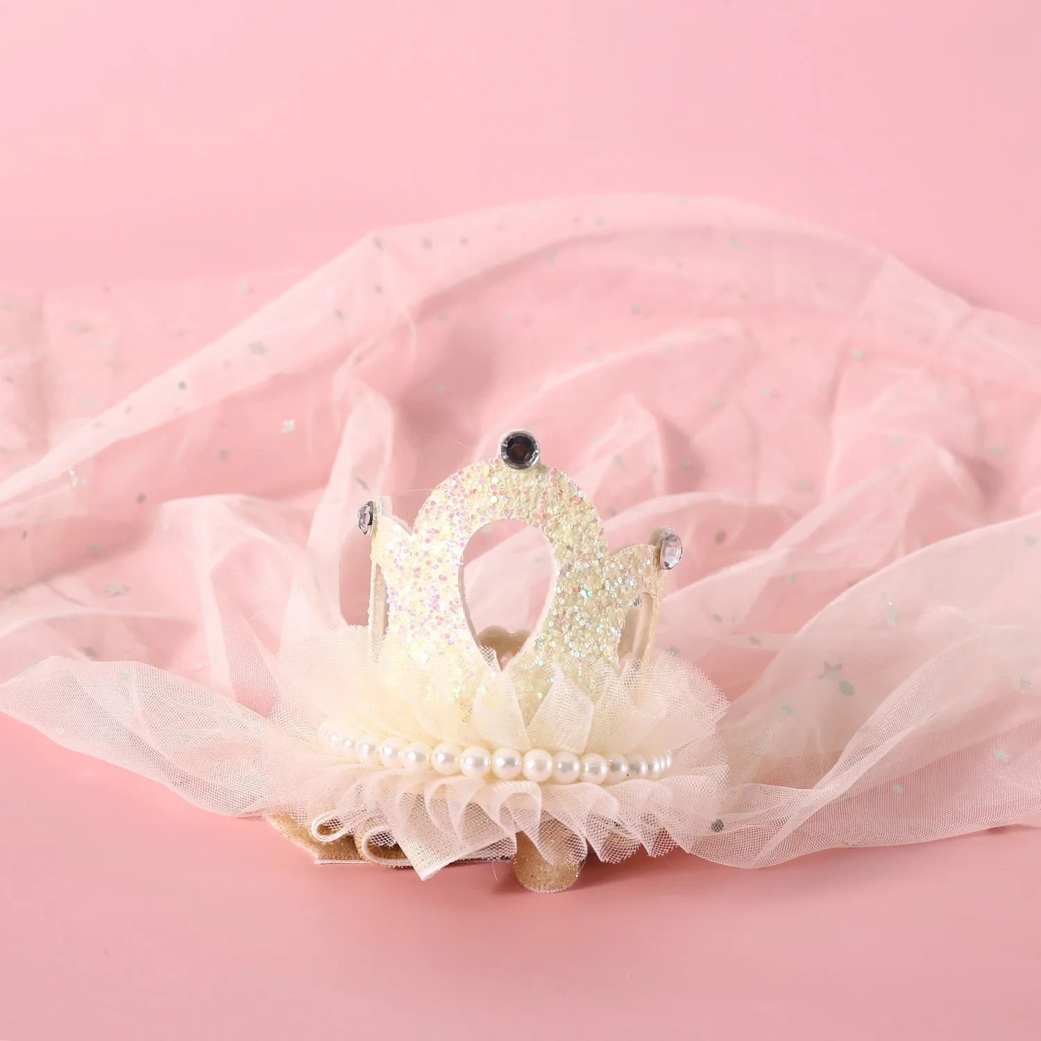 Cat wearing a princess crown headdress with a long, flowing veil in beige or pink colour.
