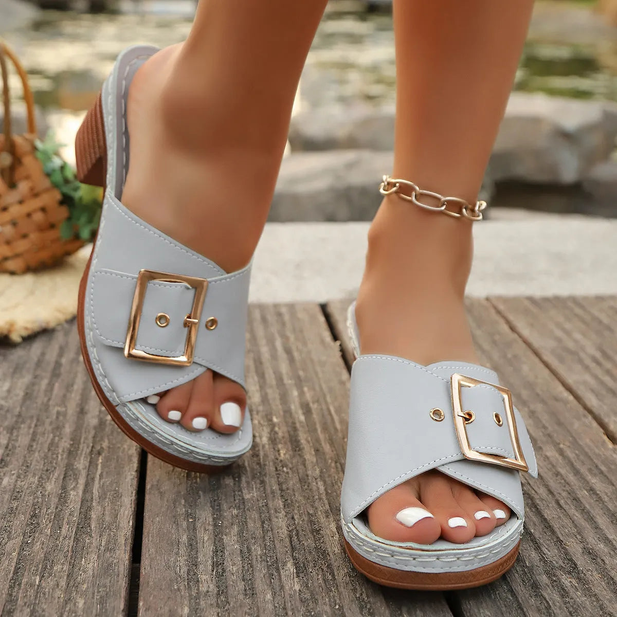 Women's black chunky heel slippers with a large silver metal buckle strap on a rubber sole.