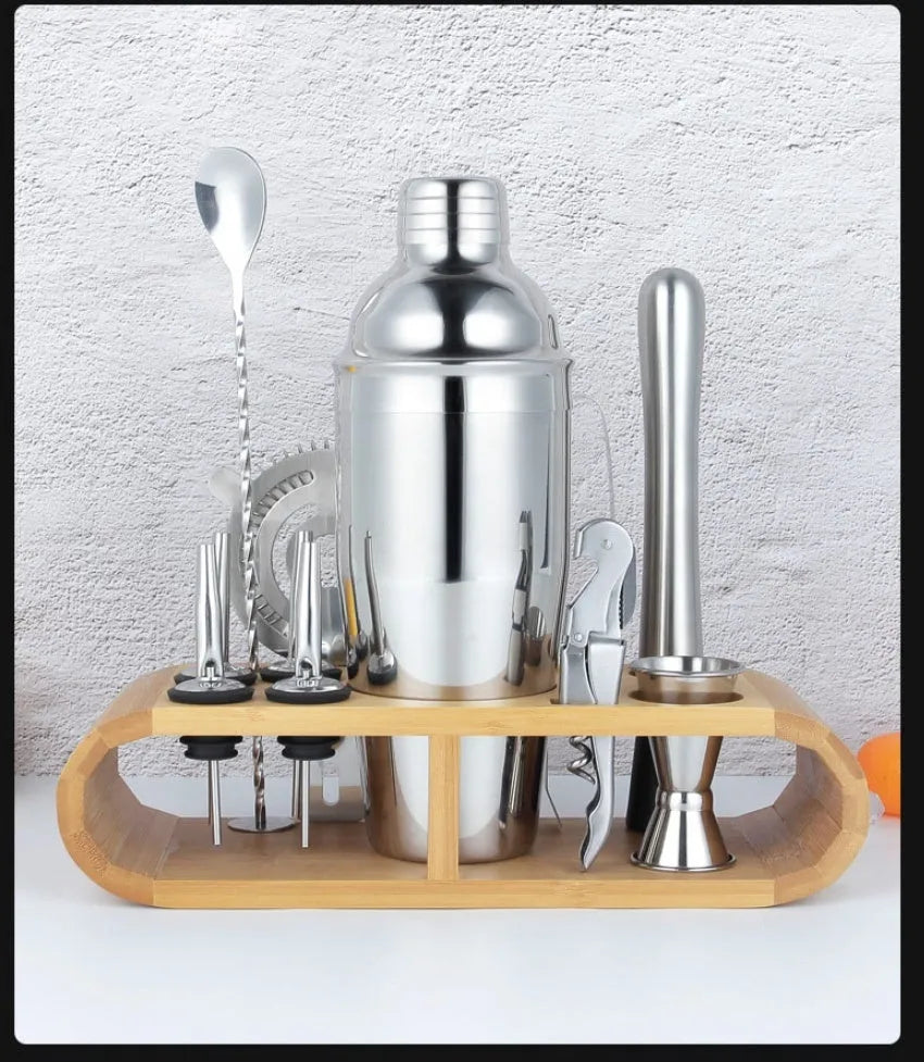 23-piece stainless steel cocktail set with shaker, jigger, strainer, and other bar tools on a wooden surface.