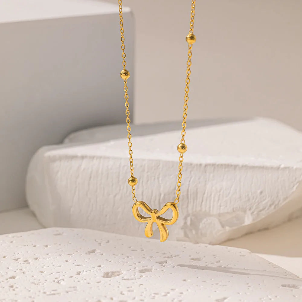 Gold bow necklace with cross chain design showing adjustable length from 41 to 50cm