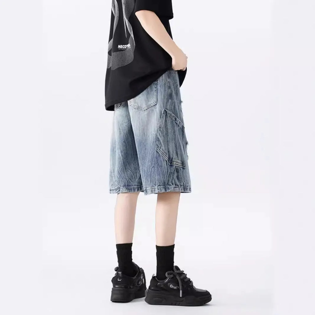 Washed black denim shorts with ripped details and loose retro fit showing front view