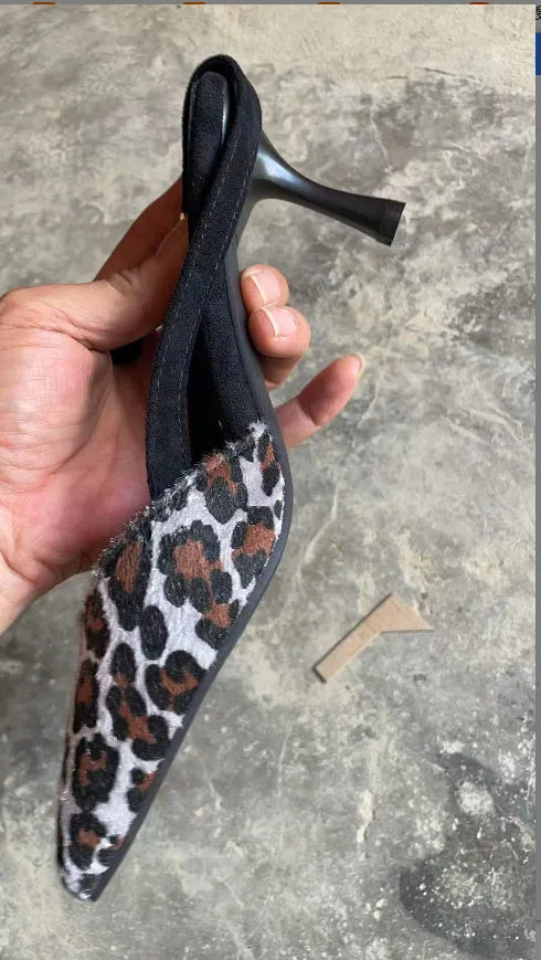 Leopard print suede women's sandals with a pointed toe on a foot mannequin.