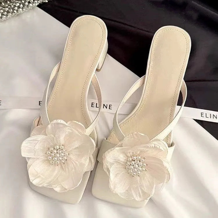 Women's cream-white satin sandals with a chunky heel and square toe on a light background.