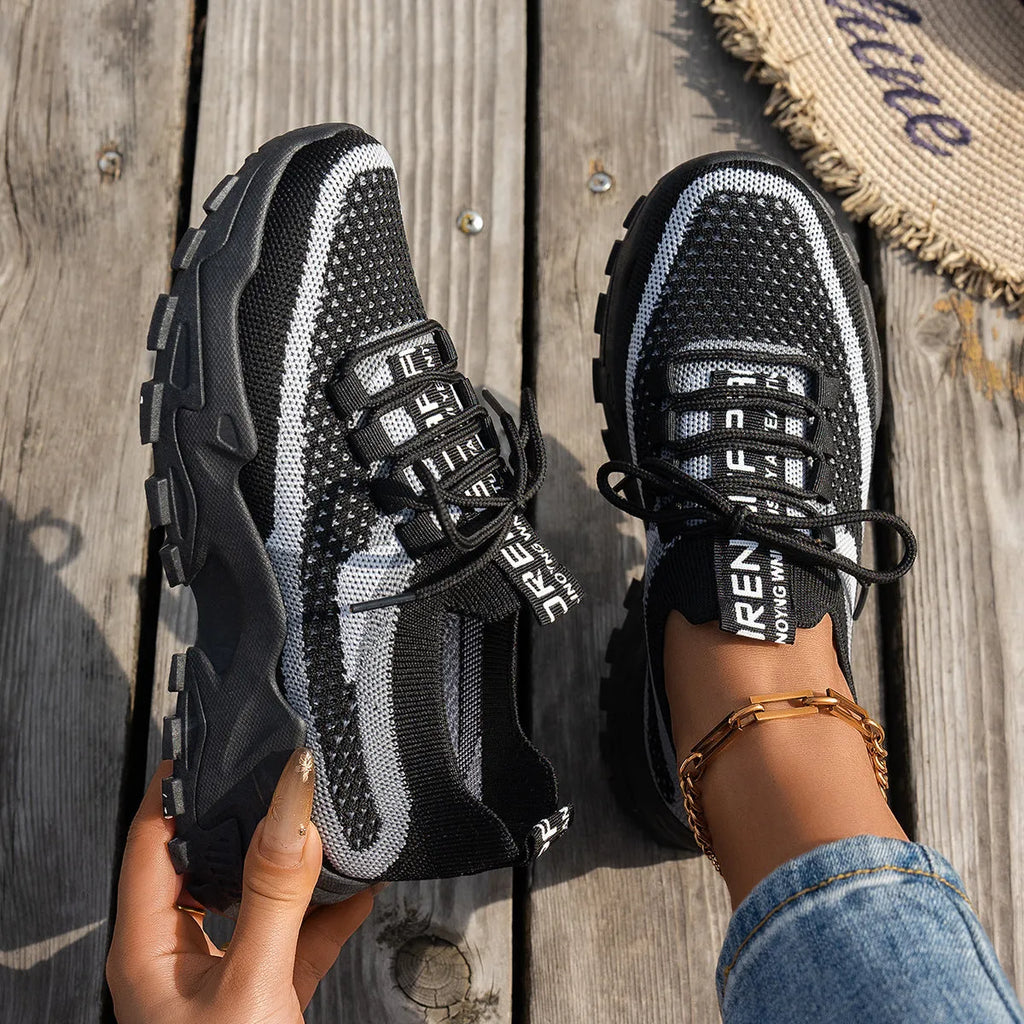 Women's Flyknit mesh sneakers in grey and white colour with flat rubber sole and lace-up front.