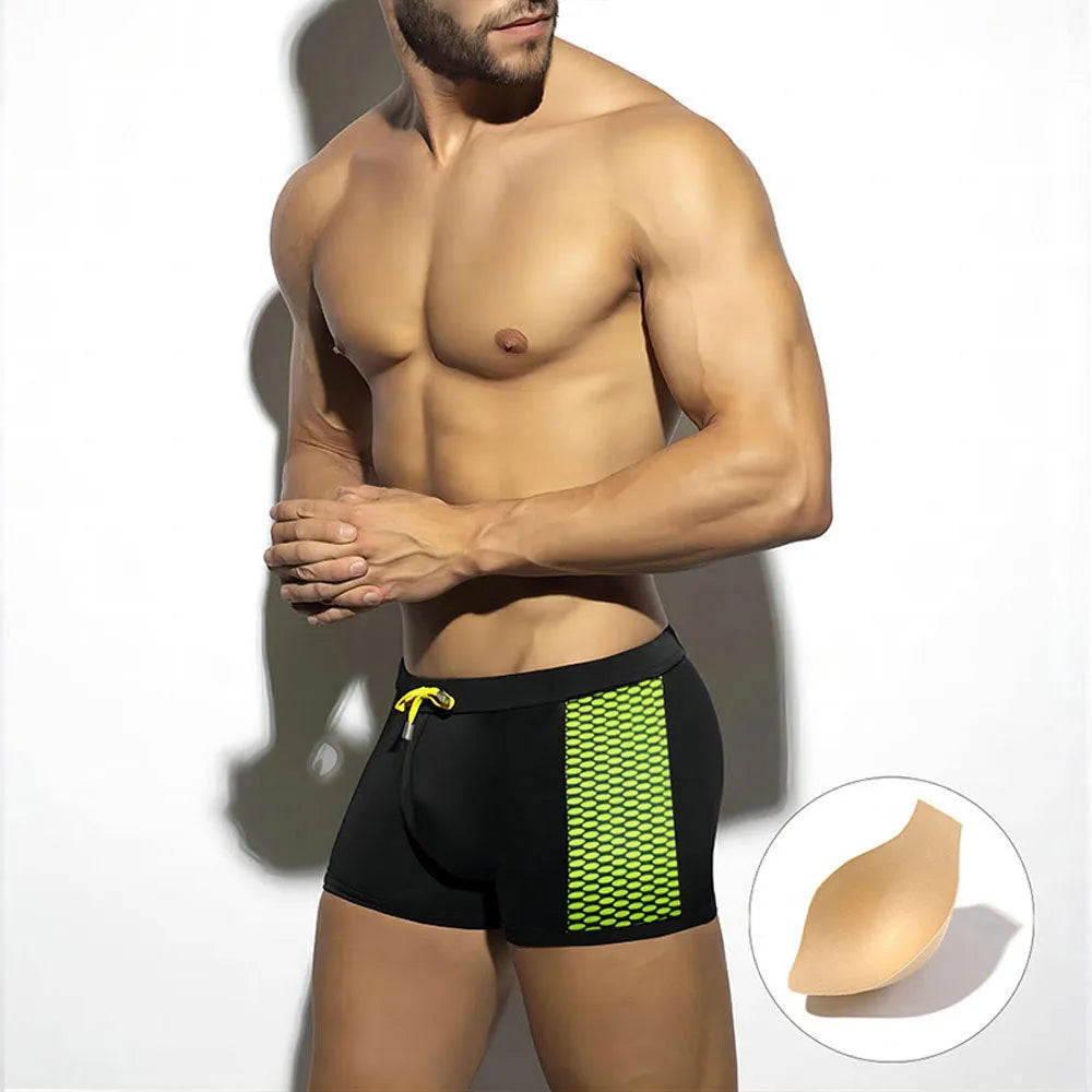 Men's black swimming boxers with white polka dot print and ribbon trim, laid flat.