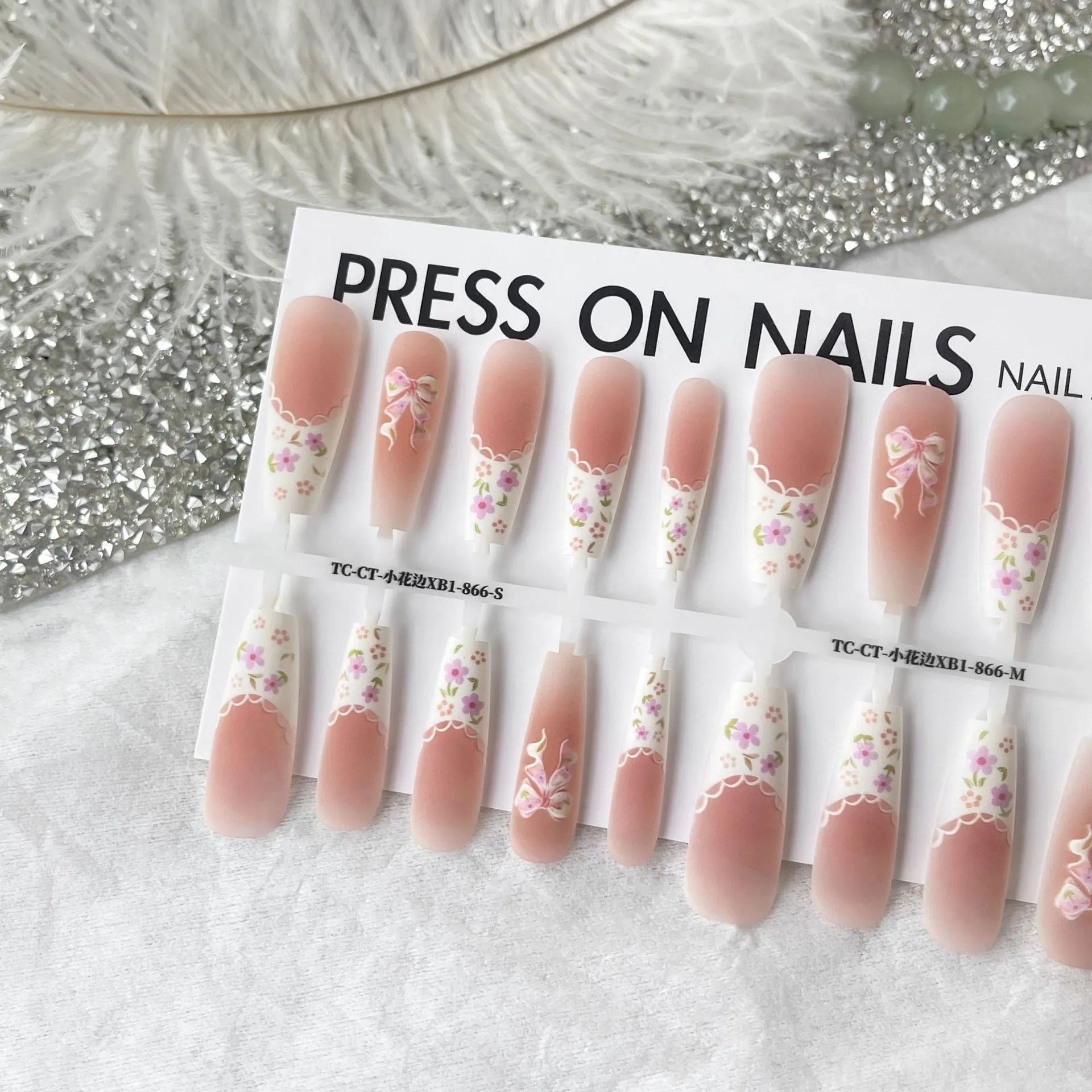 Set of 40 small floral prefabricated nail tips with long ladder velvet seal layer in white, displayed on a flat surface