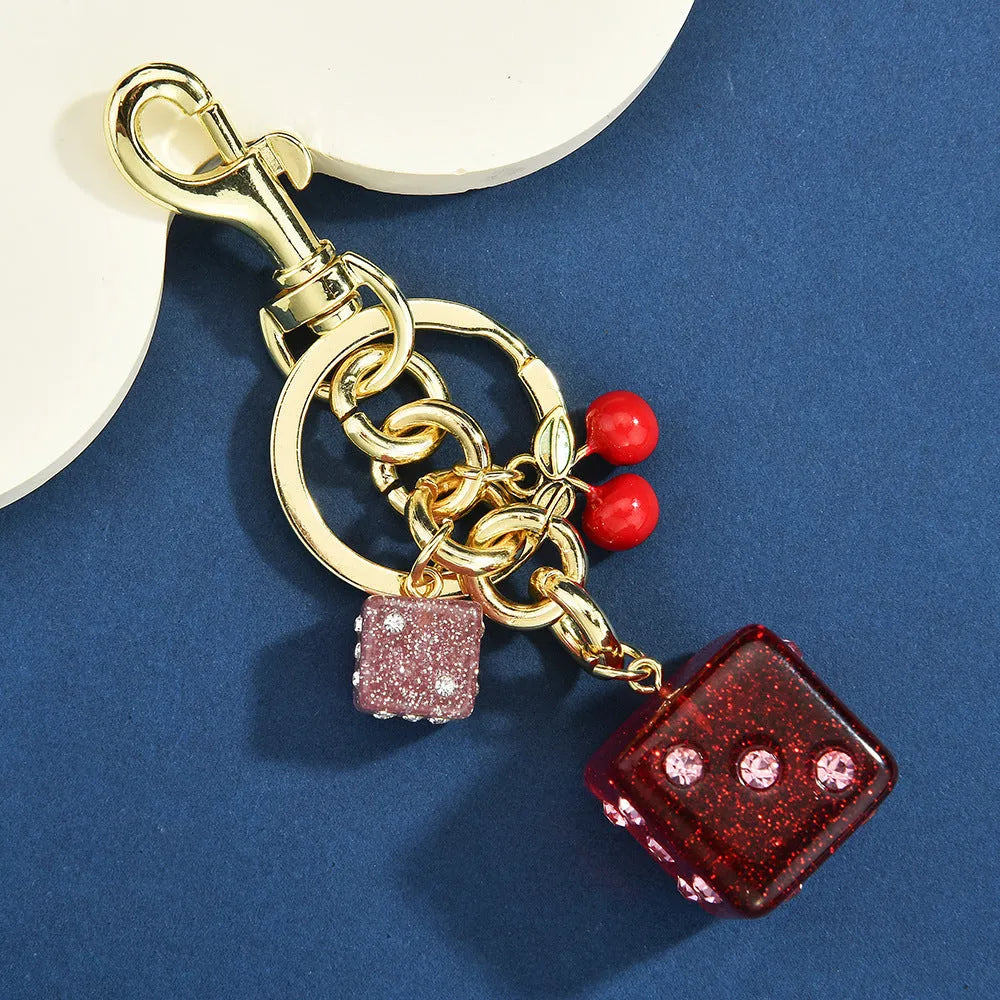 Square metal keychain pendant with a cerise two-tone dice pattern.