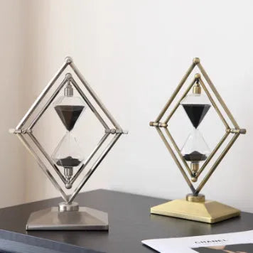 Modern zinc alloy hourglass timer on desk showing bronze frame with white sand.