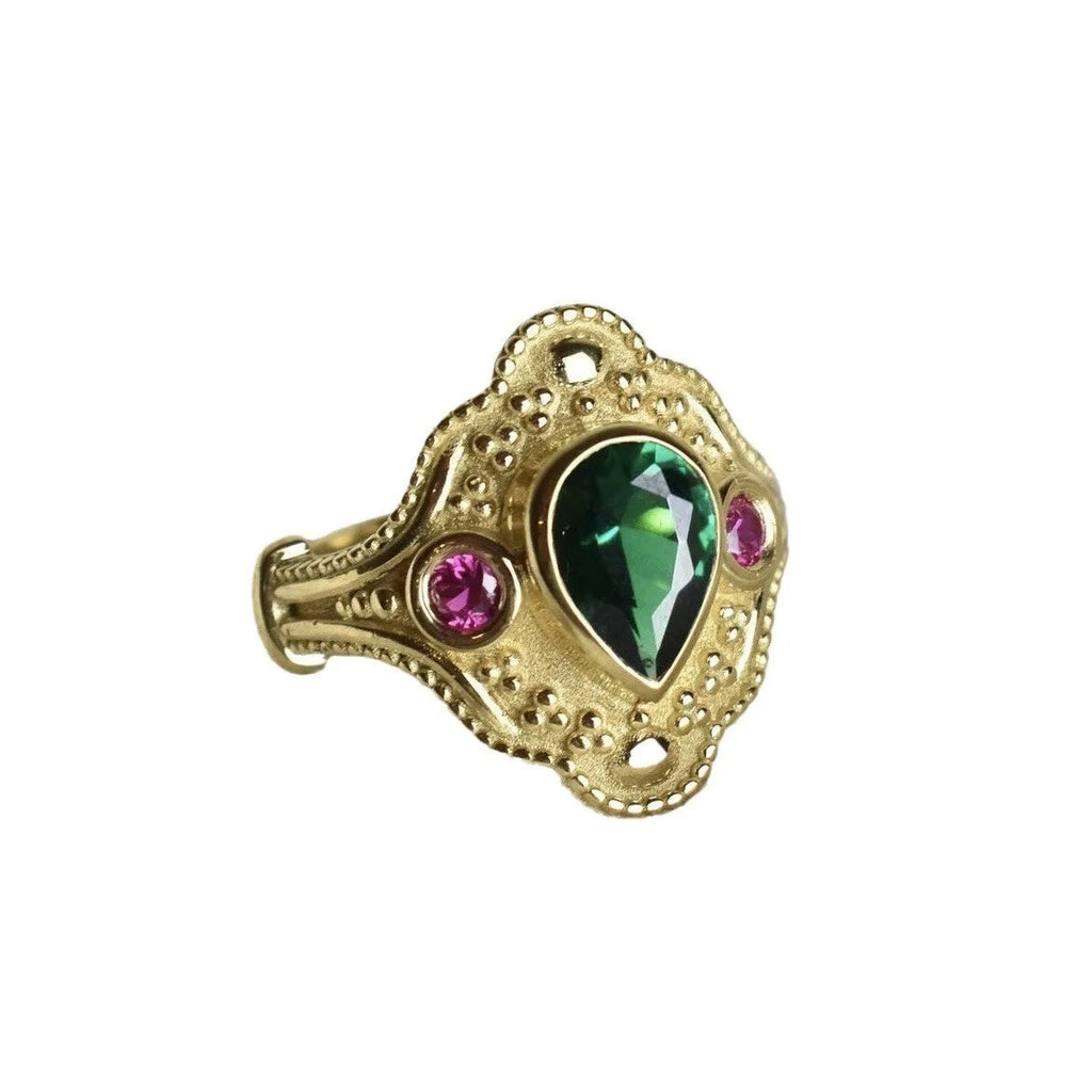 A gold-coloured women's ring with a geometric shape on a plain background.