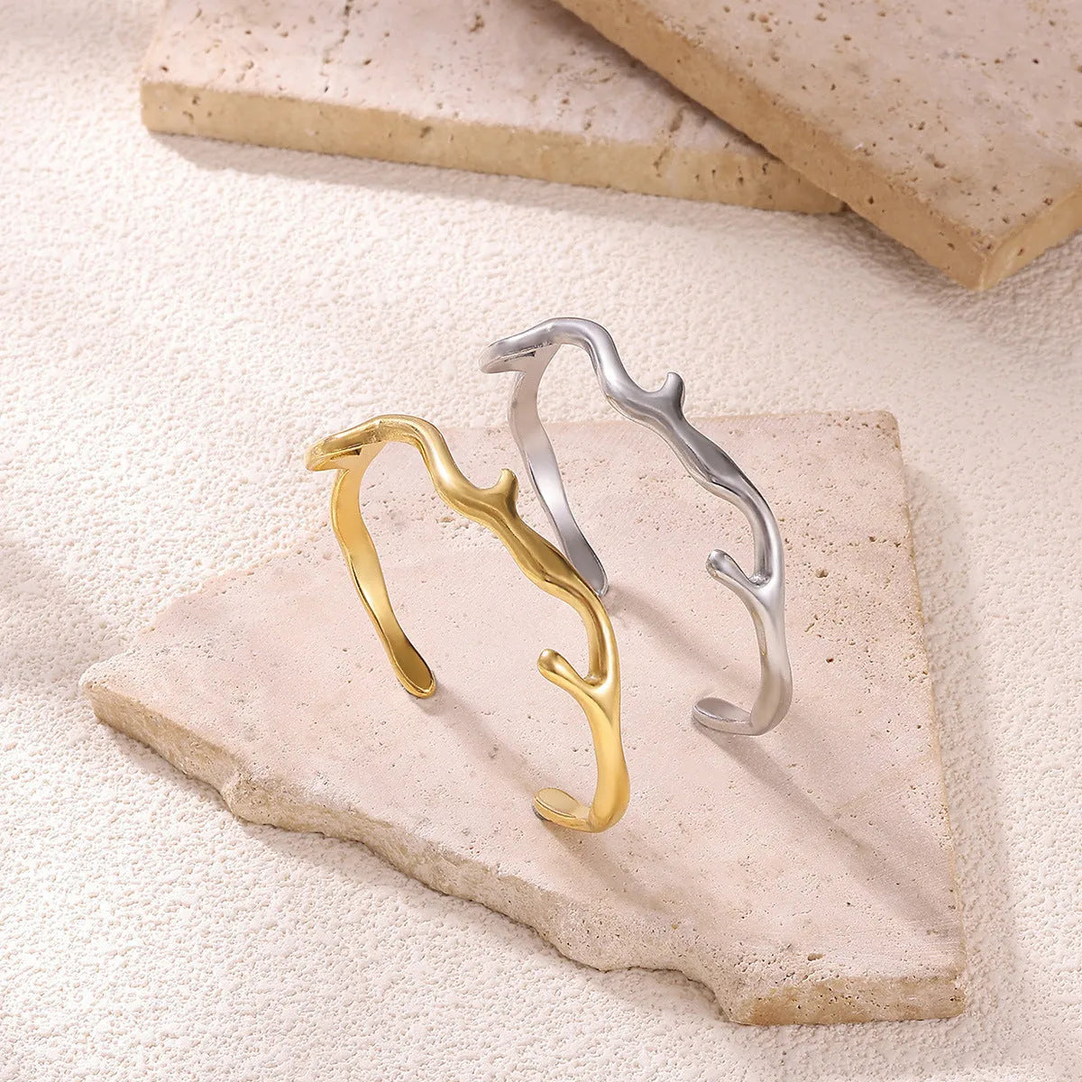 Simple irregular stainless steel gold-plated bracelet in silver finish on plain background