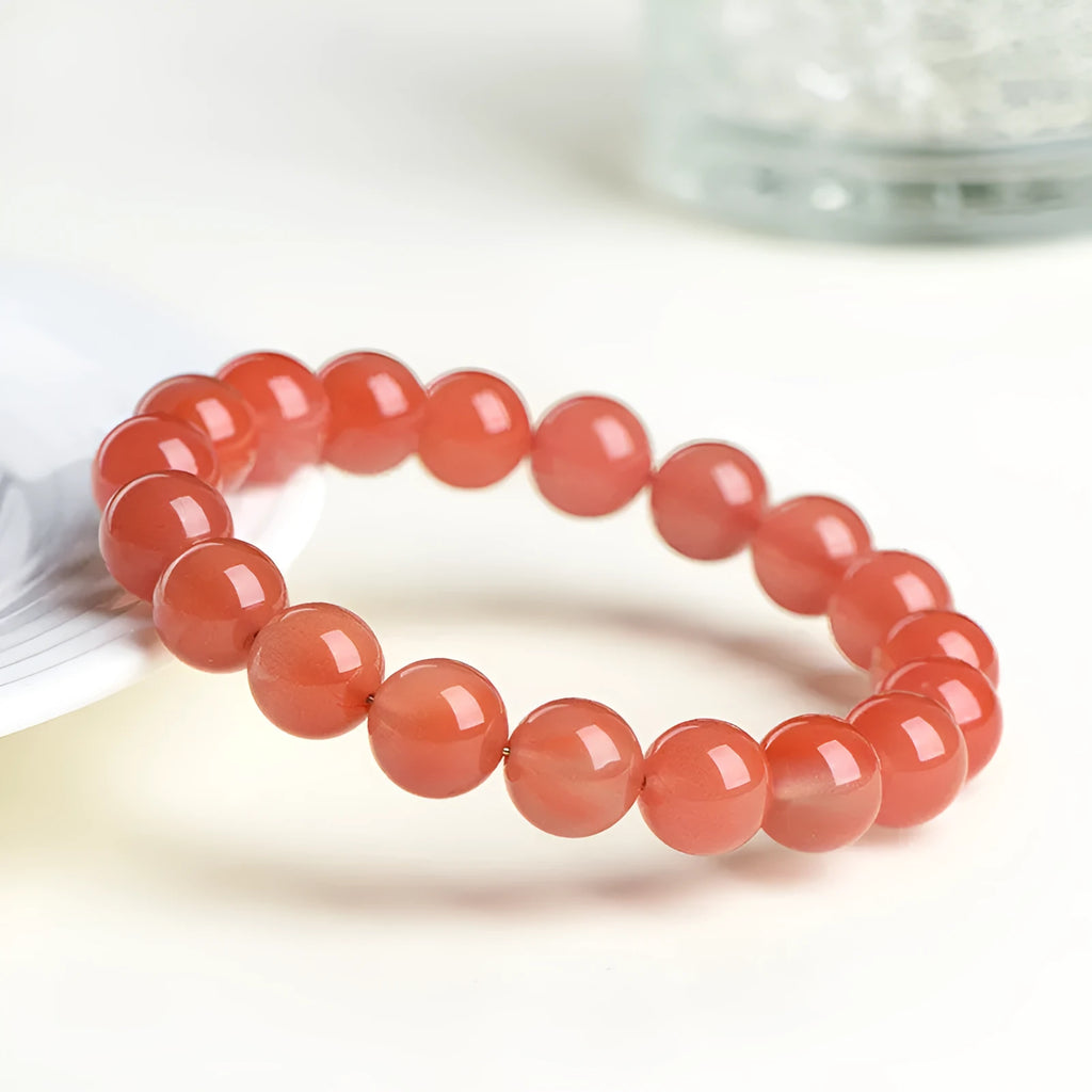 Natural cherry red agate bracelet with polished beads on a white background.