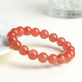 Natural cherry red agate bracelet with polished beads on a white background.