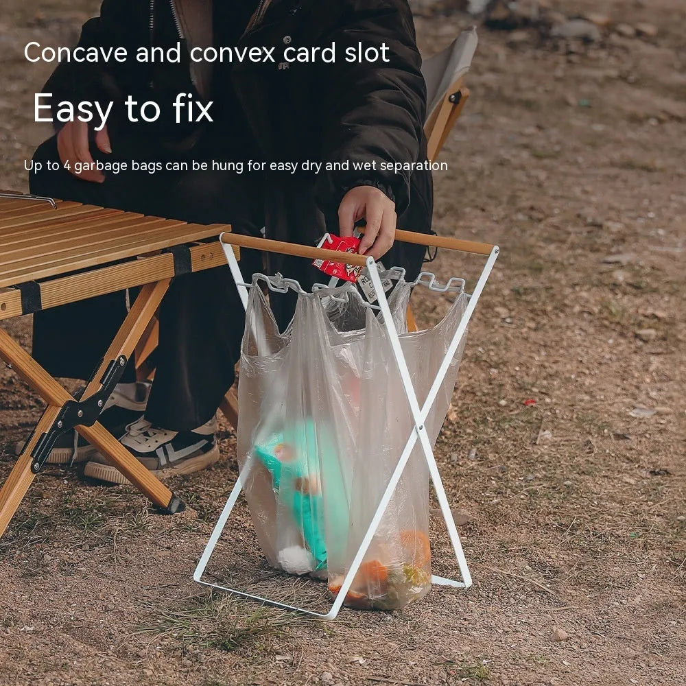 Black folding outdoor trash rack with a wooden handle, holding a rubbish sack.
