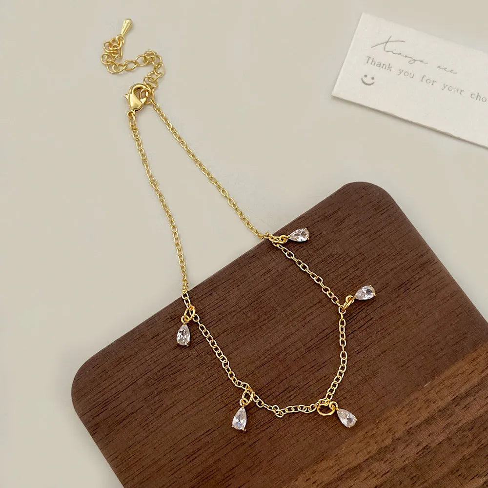Zircon geometric necklace, earrings, and anklet set with meteor shower detail on a white background.