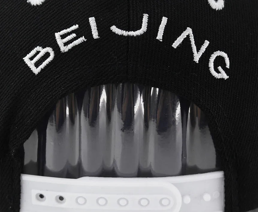 Cotton baseball cap with letter embroidery in black or white colours, showing adjustable strap and dome crown