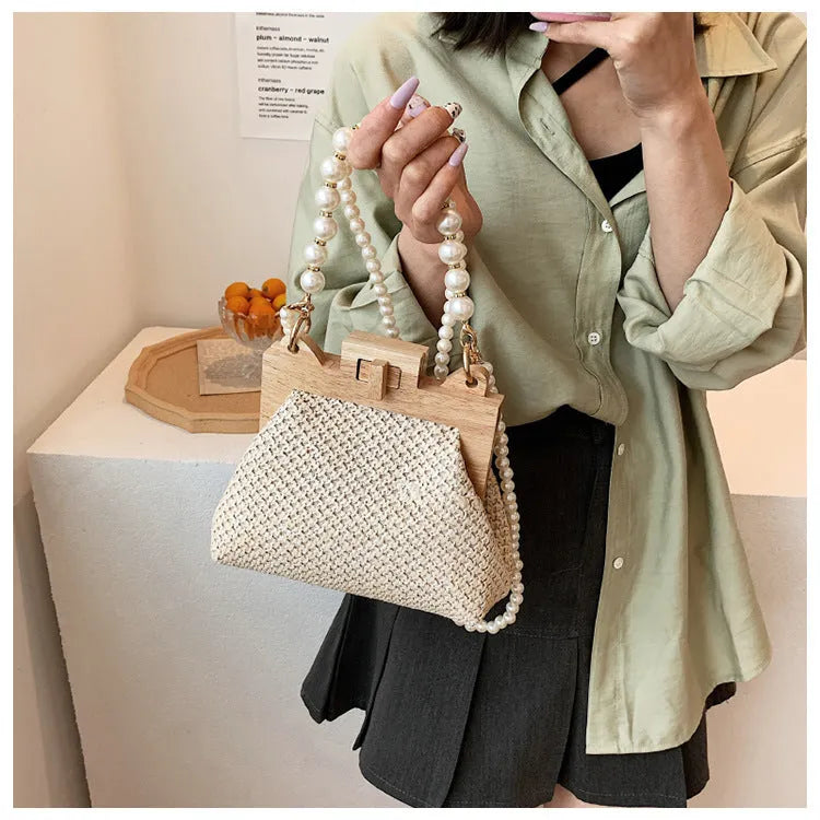 Women's woven straw shoulder bag with pearl chain strap showing interior organiser compartments