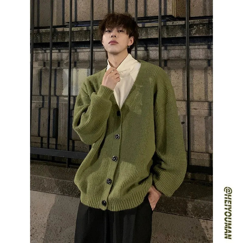 A man's loose-fitting V-neck knitted cardigan in a solid colour on a hanger.