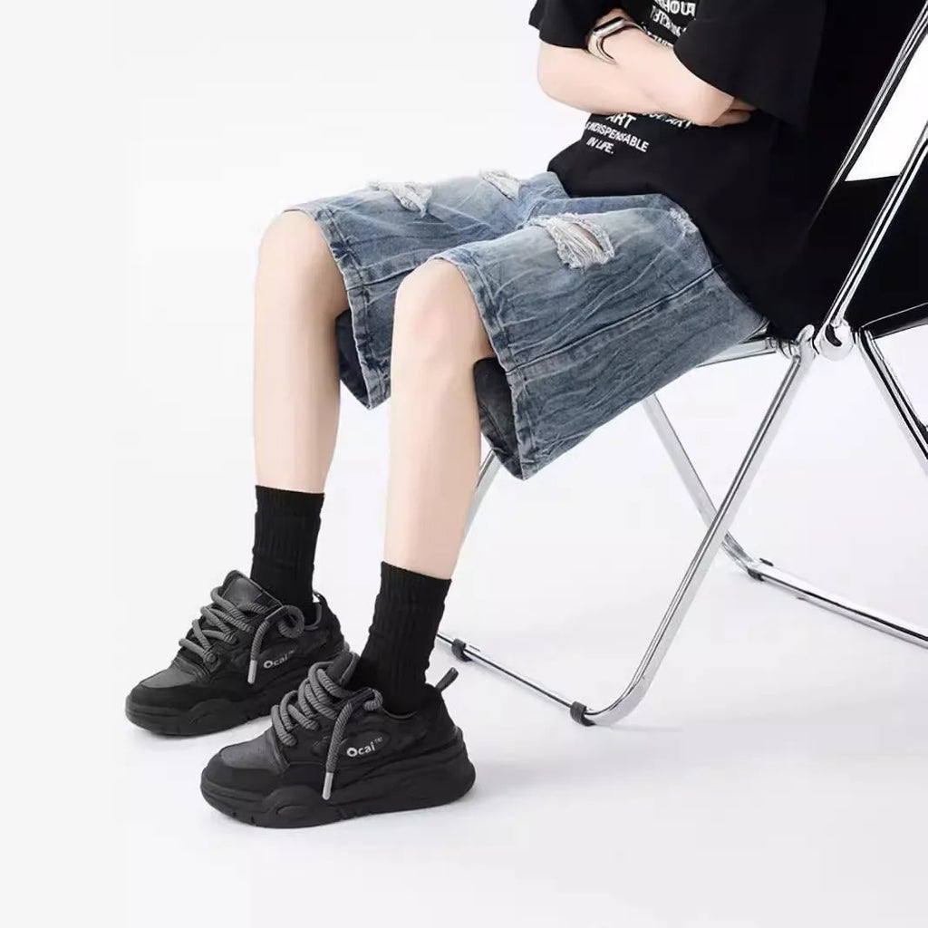 Washed black denim shorts with ripped details and loose retro fit showing front view