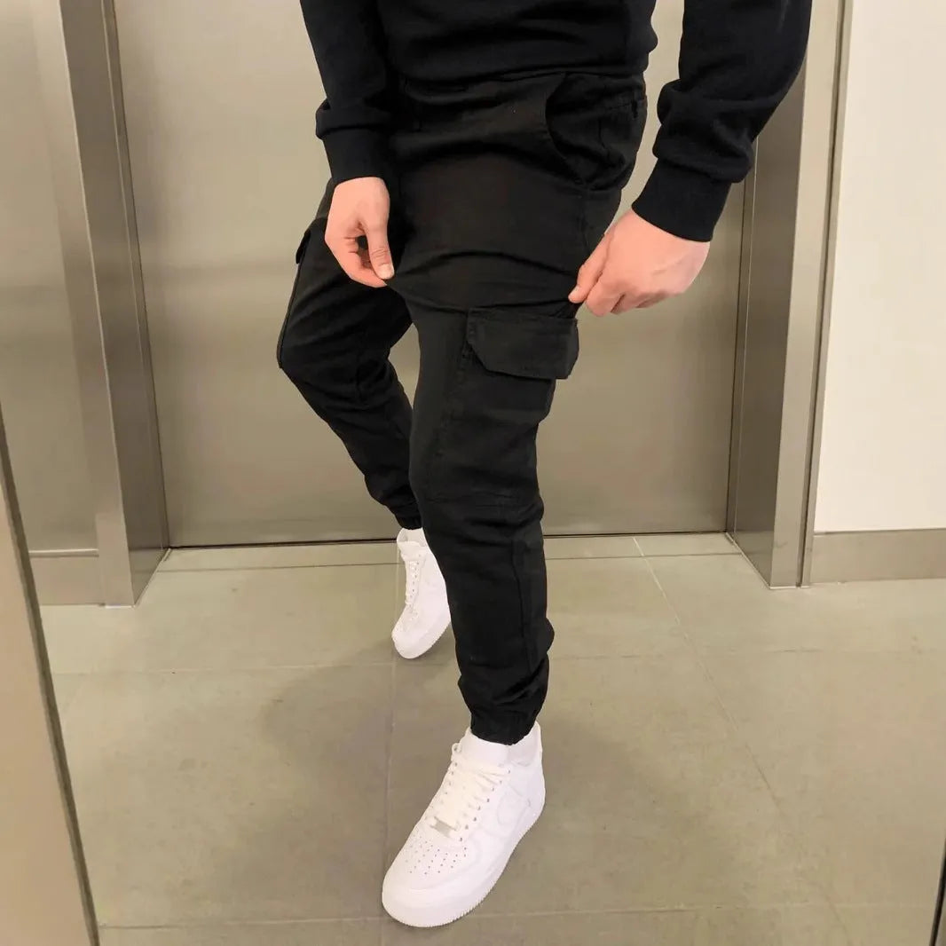 Man wearing loose light blue straight-leg casual trousers with patch pockets and an elasticated waistband.