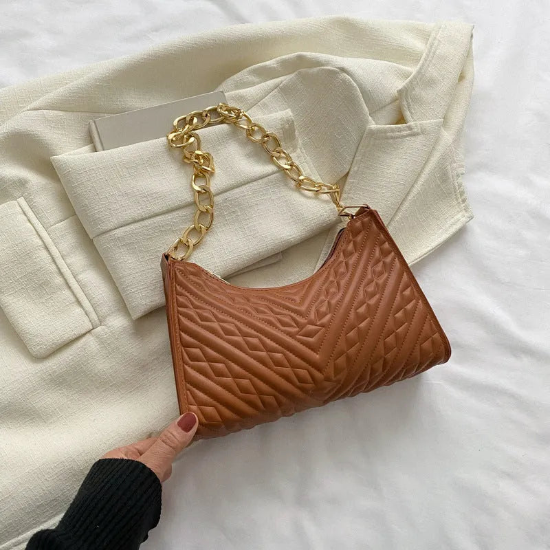 Vertical square brown PU shoulder bag with chain strap and soft handle on a table