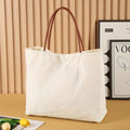 Heavyweight beige white canvas tote bag with reinforced handles on a plain background