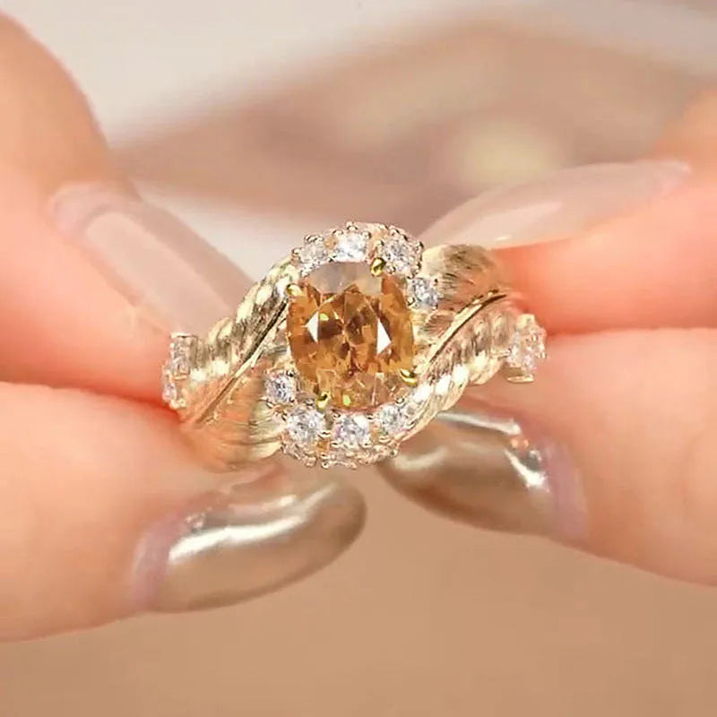 Gold-coloured copper ring with embossed feather design and yellow zircon stone inlay