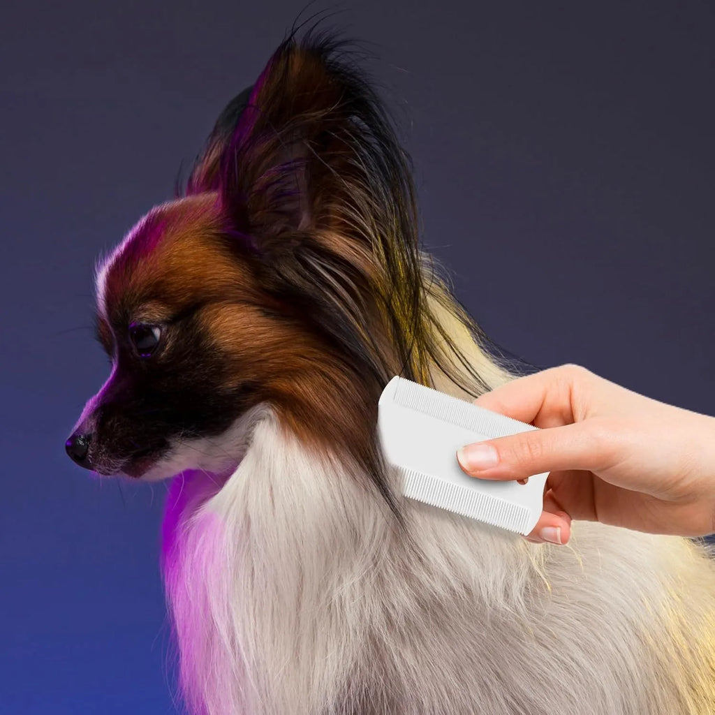Small white plastic dual-sided pet flea comb for cats and dogs on a plain background.