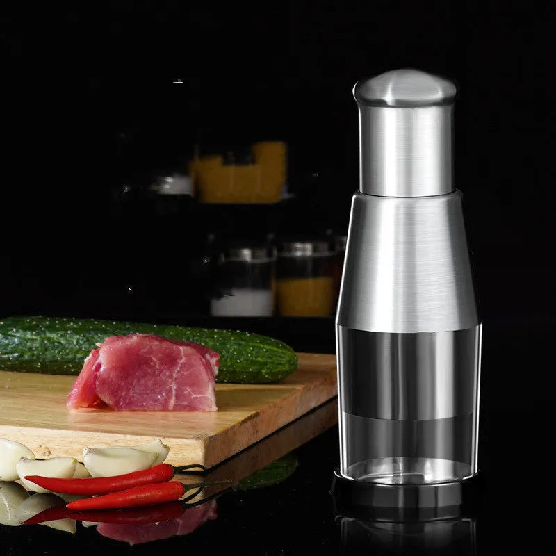 Black manual garlic crusher onion chopper with stainless steel blades on a kitchen counter